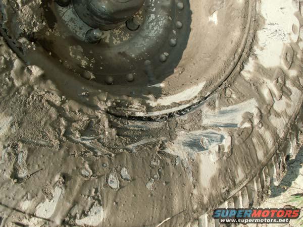 Mud-covered tire and wheel with visible lug nuts