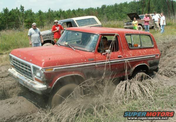 red SUV stuck in mud, another SUV behind it, people standing around