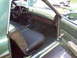 1970 Ford Ranchero - The interior of a green 1970 Ford Ranchero shows a bench seat, wood-grain dashboard accents, and a column shifter.