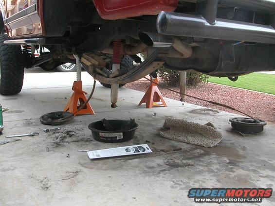 1984 Ford Bronco rear axle on jack stands, with tools and parts on the ground