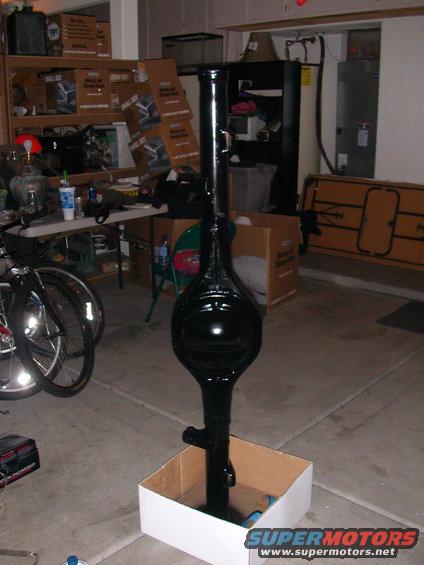 Black rear axle assembly standing in a cardboard box