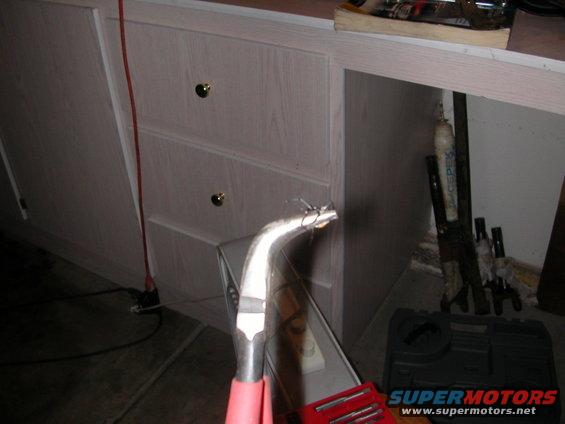 Curved metal tool with pink handle, red toolbox, and storage cabinets