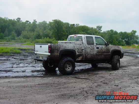 Muddy pickup truck on a dirt track with trees in the background