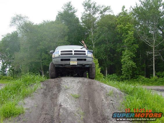 Front view of a blue pickup truck with lifted suspension on a dirt hill