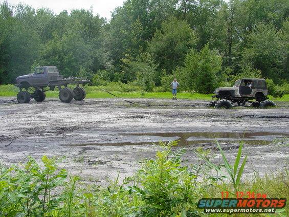 Two modified off-road vehicles stuck in mud with a person standing between them