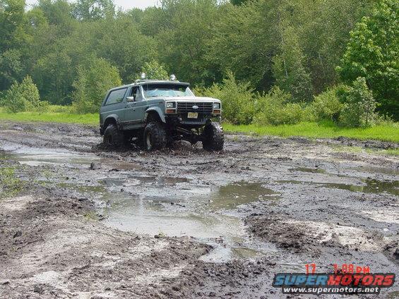 Lifted Ford Bronco driving through mud
