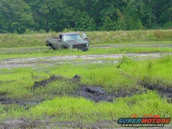 Green pickup truck stuck in mud, driver's door open