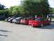 1994 Ford Probe - A line of cars is parked in a lot, with a red 1994 Ford Probe prominently featured in the foreground.