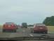 1994 Ford Probe - A red 1994 Ford Probe is seen from the rear on the highway, traveling alongside other vehicles.