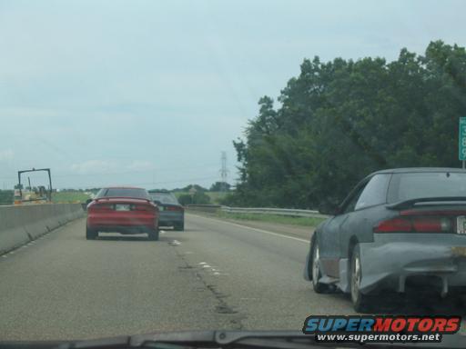 1994 Ford Probe and another car driving on a highway, rear view