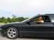 1994 Ford Probe - A man in a yellow shirt drives a black 1994 Ford Probe on a sunny day.