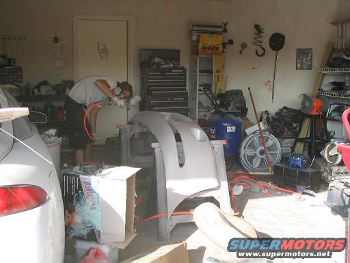 Car bumper being spray painted in a garage