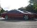 1994 Ford Probe - A red 1994 Ford Probe is parked next to another vehicle, its side profile and custom wheels.