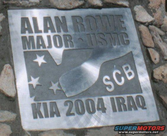 Metal memorial plaque with engraved text and stars, set in stone