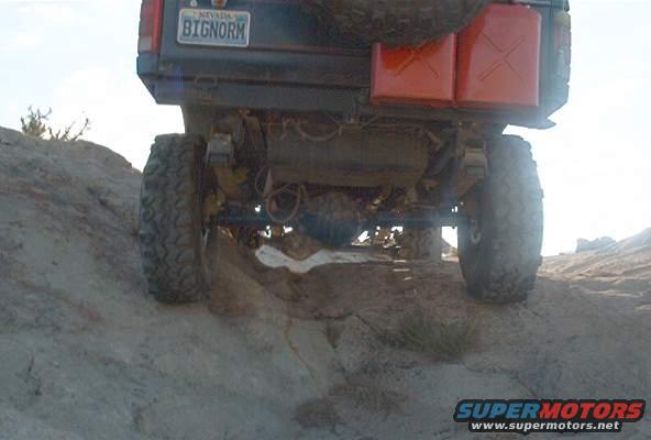 Rear view of a dark-colored Ford Bronco with two red jerrycans mounted on the back and a spare tire