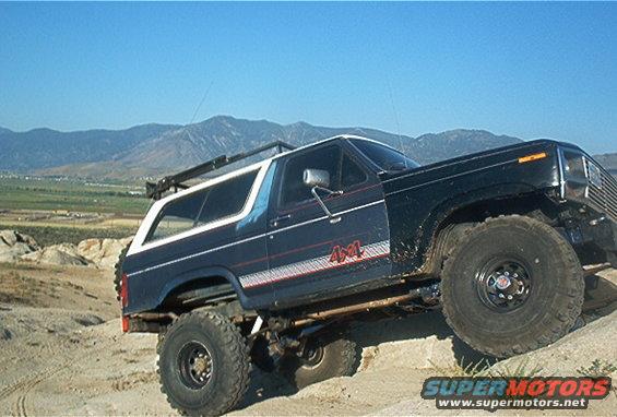 Ford Bronco with 4x4 decal on side, lifted suspension, off-roading on dirt mound