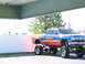 1991 Ford Bronco - A custom-painted, lifted pickup truck is parked under an overhang.
