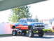 1991 Ford Bronco - A custom blue pickup truck with flame graphics is parked outside.