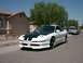 1996 Ford Probe - A white 1996 Ford Probe with a black hood and racing stripes is parked in front of a house.