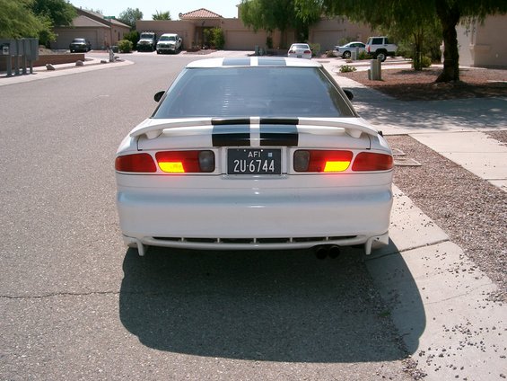 Rear view of a white 1996 Ford Probe with black racing stripes on the trunk and roof