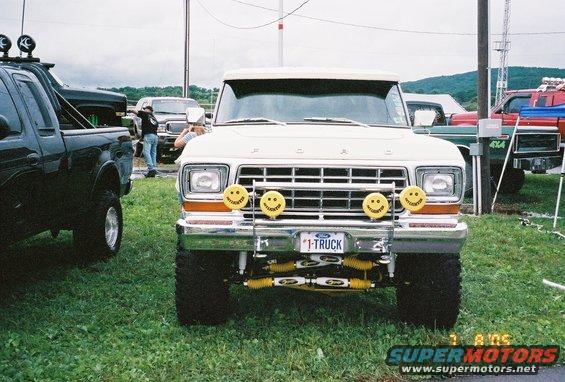 White Ford truck front view with smiley face lights and "1-TRUCK" license plate