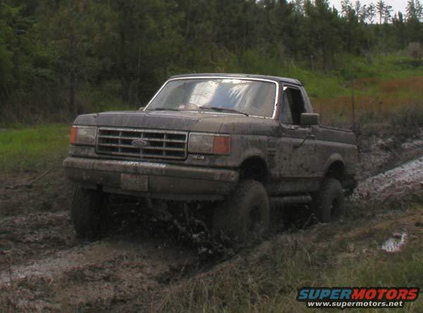 Mud-covered 1987-1991 Ford Bronco driving through deep mud