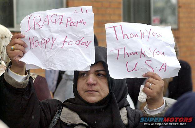 Woman holding two signs, one reading 'IRAQI People Happy today' and the other 'Thank You Thank You U.S.A.'