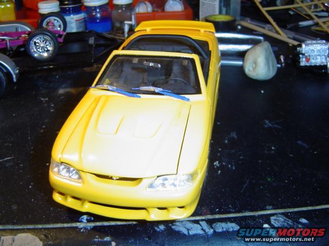 Yellow model car front view on a black surface with hobby supplies