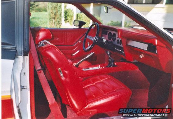 Red interior of a 1978 Ford Mustang II, showing seats, dashboard, steering wheel, and door panel