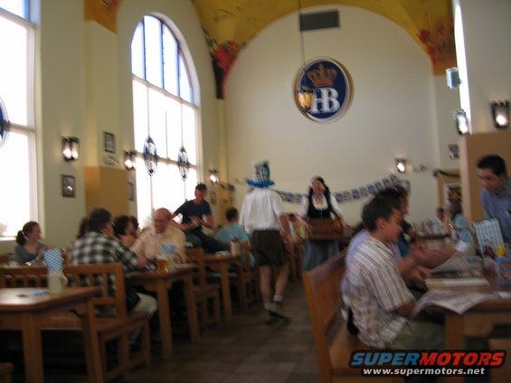 Interior of a restaurant with people at tables, a man in lederhosen, and a woman in dirndl