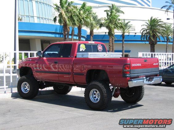 Red lifted Dodge Ram pickup truck with toolbox and decals