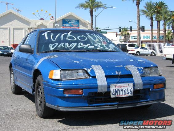Blue Honda CRX with 'TURBO DB' and 'Dang Bros!' written on windshield in white. Duct tape on front bumper