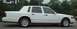 1997 Ford Crown Victoria - Side profile of a white sedan with tinted windows and wire-spoke wheels.