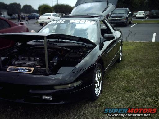 Black 1995 Ford Probe with hood and trunk open, parked on grass