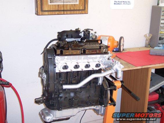 Engine on an orange stand, with a workbench and tools in the background