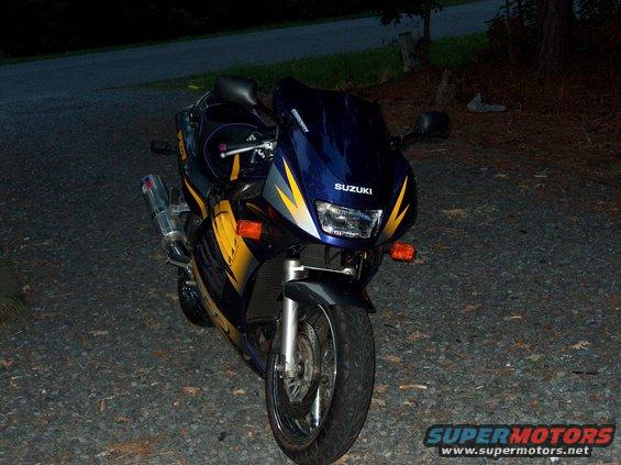 Blue and yellow Suzuki motorcycle parked on gravel, front view