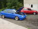 1998 Volkswagen Jetta - Two Volkswagen Golf Mk3s are parked in a driveway, one with its hood open, revealing the engine bay.