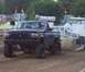 1994 Ford F-150 - A modified pickup truck competes in a truck pull event, kicking up dirt as it goes.