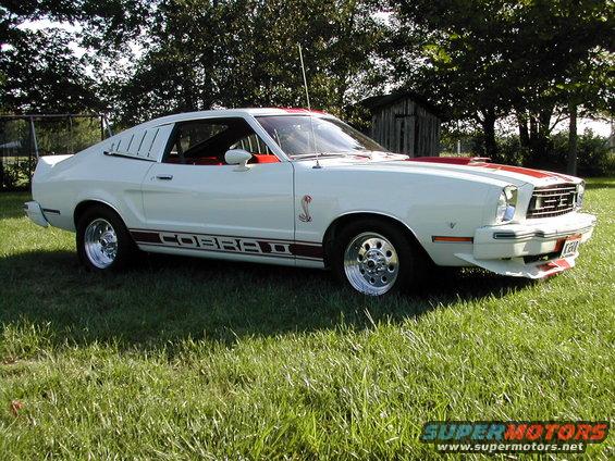 White 1978 Ford Mustang II Cobra II with red stripes and side decals, parked on grass