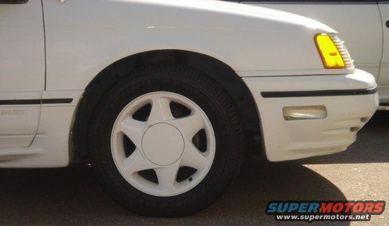 White 1991 Ford Taurus front corner with a five-spoke wheel and yellow turn signal