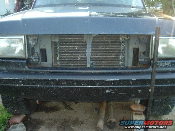 Dark blue Ford Bronco front end with missing grille, showing radiator. Headlights intact. Bumper chipped