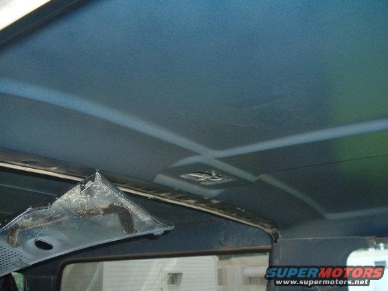 Blue vehicle interior ceiling with visible damage to a trim piece