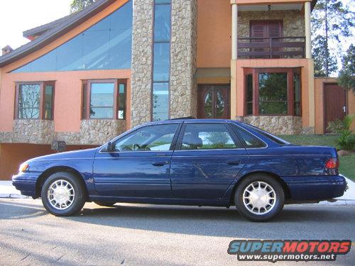 Blue 1995 Ford Taurus sedan parked in front of a modern house, side view