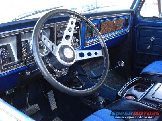 1978 Ford Bronco interior with blue seats, wood-grain trim, and aftermarket steering wheel