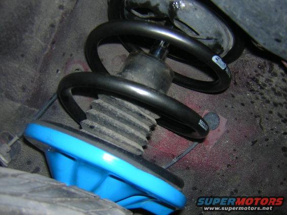 Close-up of a car's front strut assembly with a blue spring seat and black coil spring