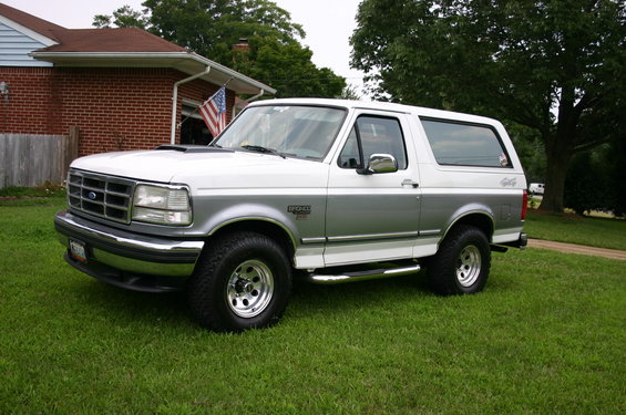 White and silver Ford Bronco with chrome side steps parked on grass