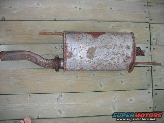 Rusty exhaust muffler and pipe on wooden planks