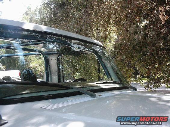 1978 Ford Bronco windshield and roofline with a white pickup truck visible in the background