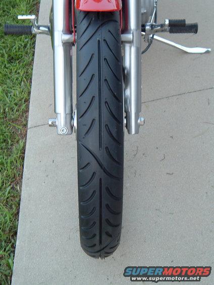 Motorcycle front tire and chrome forks, red bodywork visible above
