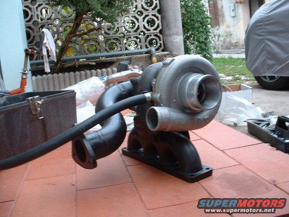 Turbocharger with black exhaust manifold and hose, resting on terracotta tiles